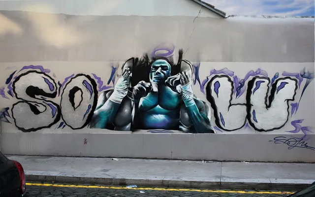 Een blauwe vechtersfiguur, omlijst door krachtige, veelkleurige graffitiletters.